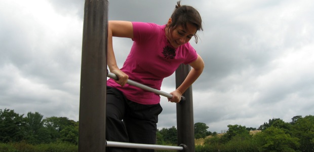 A woman learning how to exercise, working out on a climbing frame